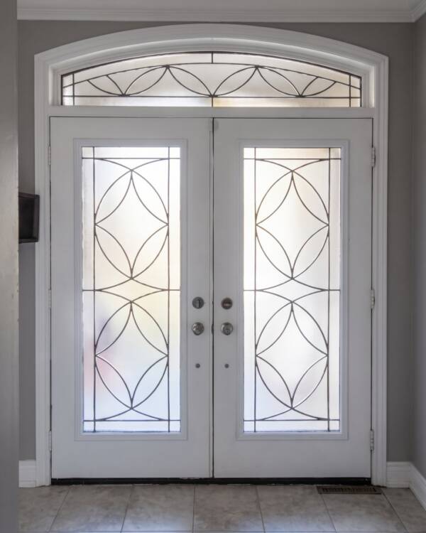 Custom wrought iron inserts in a double door with an arched transom