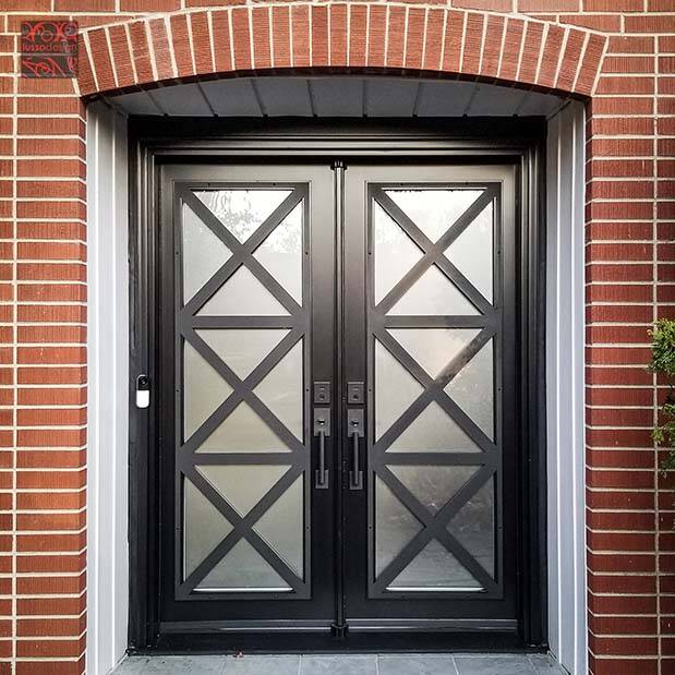 A black double door with geometric glass under a brick arch