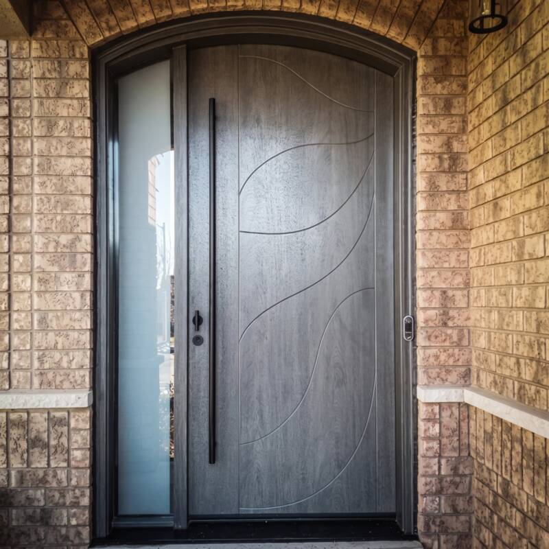 An arched grey woodgrain door with a frosted sidelite