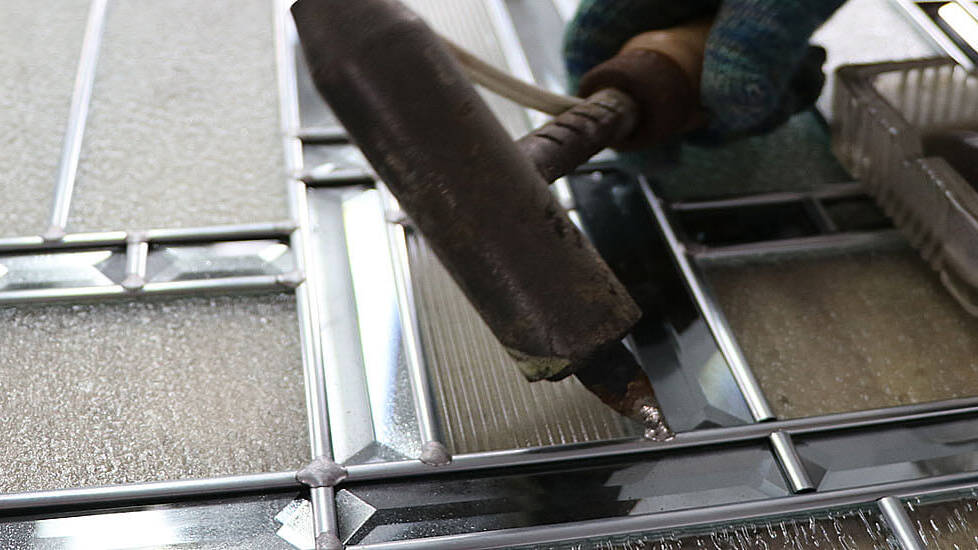 The joints of a bevelled glass panel being soldered
