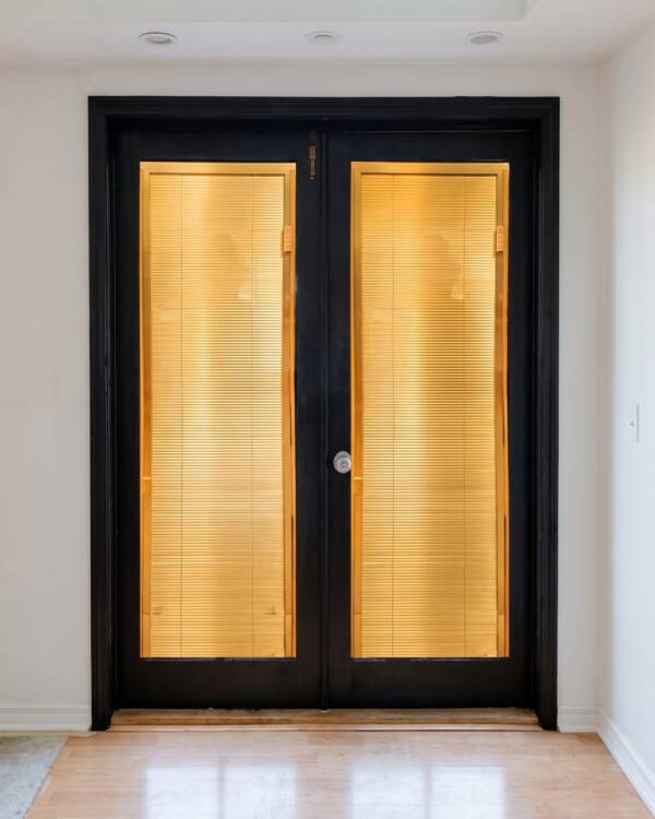 A black double door with gold blinds, lit from inside