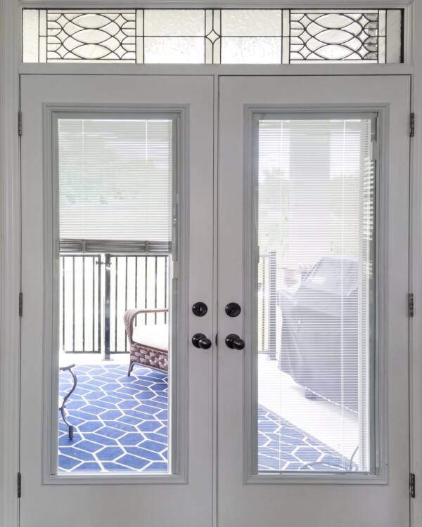 French doors with blinds and a decorative transom above